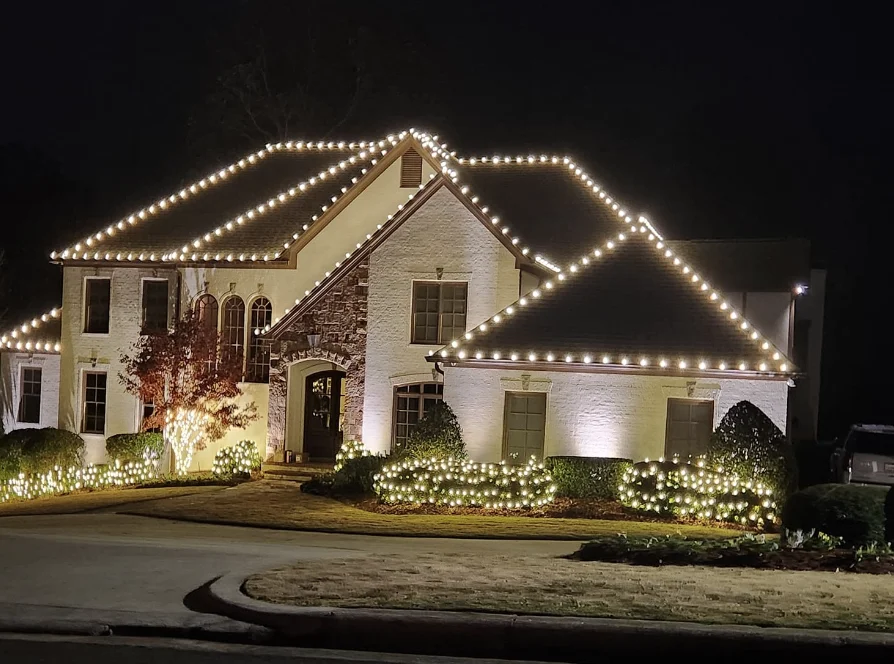 Large home with every roof line and shrub covered in white lights